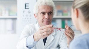 Optician giving glasses to the patient